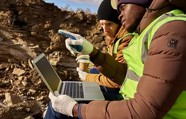 maintenance planners with a laptop at a mine site discussing potential wear challenges