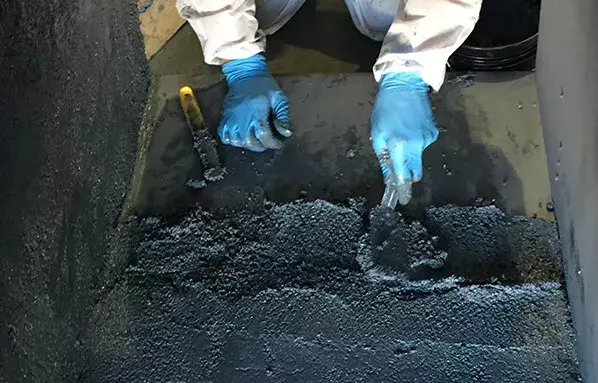 worker applying a trowel-grade wear compound inside a mining equipment for abrasion and erosion protection